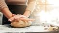 Female hands kneading dough, sunset background. Woman cooking bakery at kitchen table. Homemade cuisine, pastry making, confectionery concept