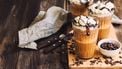 Homemade coffee coctail with whipped cream and liquid chocolate on rustic wooden background
