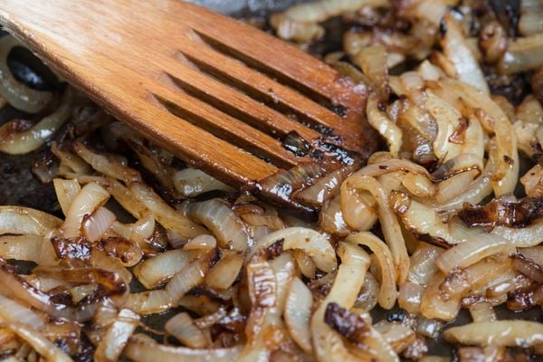 Onions caremelizing in frying pan with wooden cooking spatula