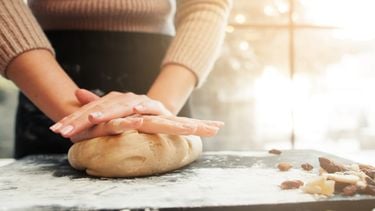 Female hands kneading dough, sunset background. Woman cooking bakery at kitchen table. Homemade cuisine, pastry making, confectionery concept