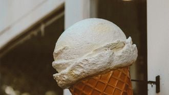 bolletje vanille-ijs op hoorntje aan gevel