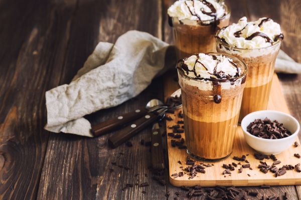 Homemade coffee coctail with whipped cream and liquid chocolate on rustic wooden background