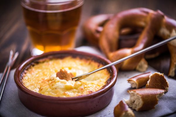 worming cheese fondue with pretzel at winter evening
