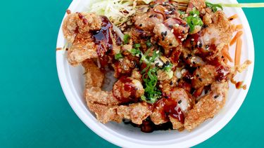 Deep fried chicken basked in teriyaki sauce with vegetables, spice, and rice.