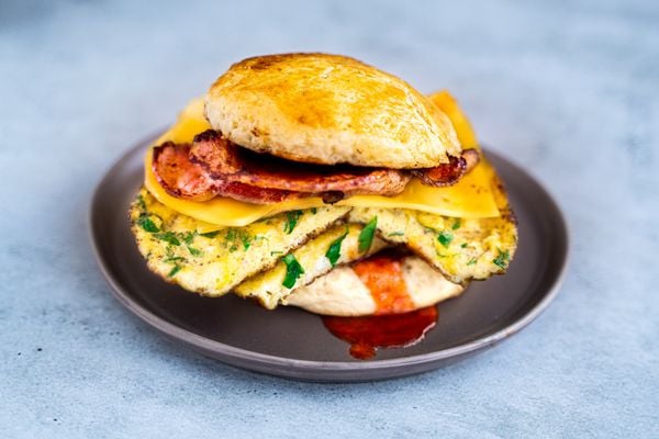 Breakfast sandwich on a scone with bacon, cheese and omelet