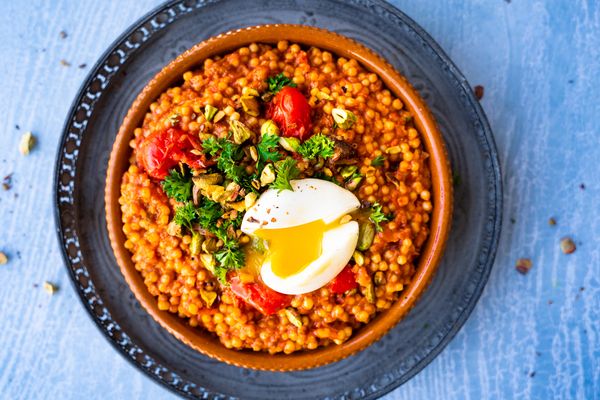 spicy pearl couscous with tomato, pistachio, parsley and an egg